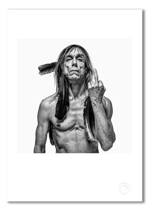 Classic black and white portrait of Iggy Pop by Gavin Evans, 1996. Finger raised, bare-chested with black feathers. A3 giclée print with white border, Iggy Pop Collection.