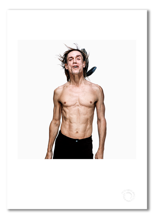 Colour portrait of Iggy Pop by Gavin Evans, 1996. Mouth open mid-expression, bare-chested with feathers, white background. A3 giclée print with white border, Iggy Pop Collection.
