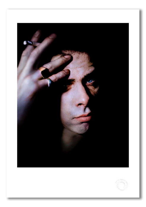 Colour portrait of Nick Cave by Gavin Evans, 1989. Staring at viewer with hand on forehead holding cigarette. A3 giclée with white border, Nick Cave Collection.