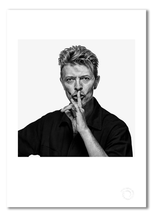David Bowie black and white portrait by Gavin Evans, 1995. Direct gaze with shushing pose. A3 giclée print with white border, Bowie Collection.