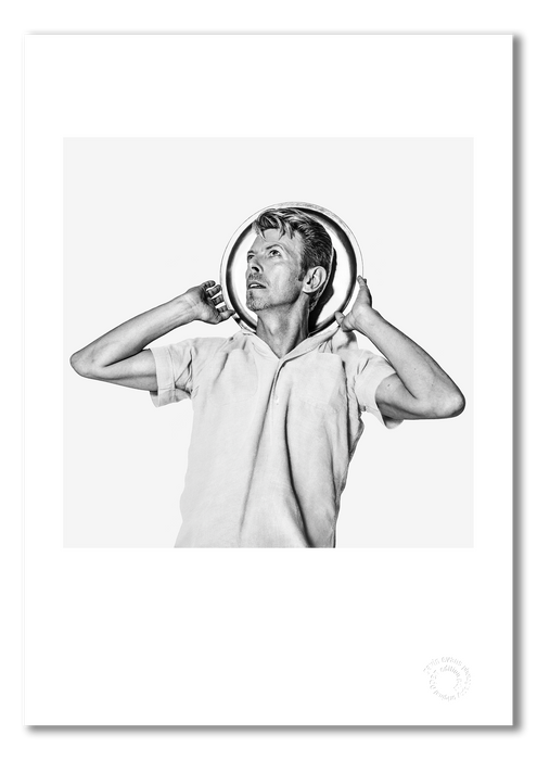 Black and white portrait of David Bowie by Gavin Evans, 1995. Humorous pose with drinks tray as halo. A3 giclée with white border, Bowie Collection.