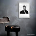 Framed B&W portrait of David Bowie by Gavin Evans, 1995. Shushing pose, direct eye contact. Displayed in dilapidated monochrome room, Bowie Collection.