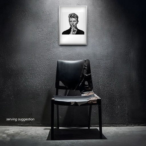 Framed black and white portrait of David Bowie by Gavin Evans. Iconic hush gesture, displayed in raw interior, David Bowie Collection.