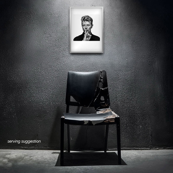 Framed black and white portrait of David Bowie by Gavin Evans. Iconic hush gesture, displayed in raw interior, David Bowie Collection.
