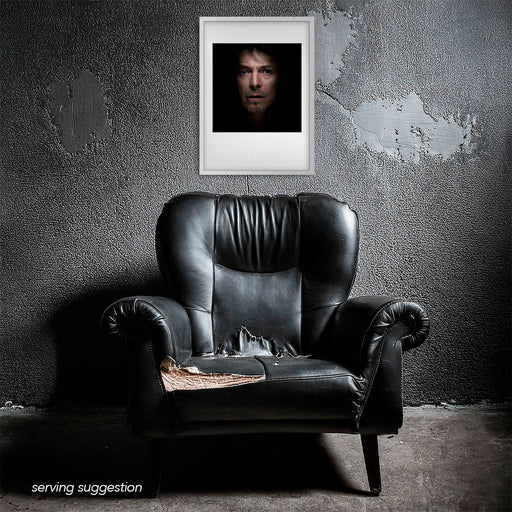 Framed colour portrait of David Bowie by Gavin Evans, 1995. Caught off-balance, displayed in a dilapidated monochrome room. Bowie Collection.