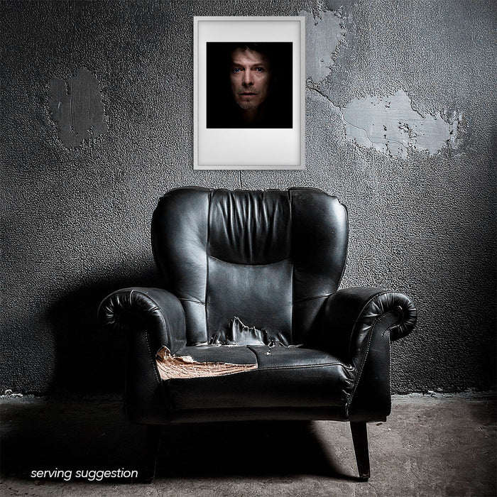 Framed colour portrait of David Bowie by Gavin Evans, 1995. Caught off-balance, displayed in a dilapidated monochrome room. Bowie Collection.