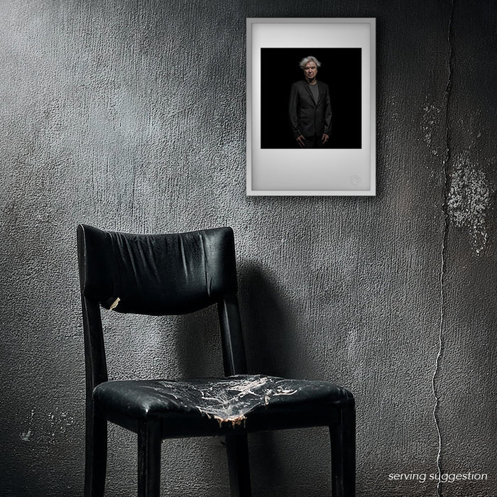 A framed view of the David Byrne A3 colour portrait by Gavin Evans, styled within a distressed room. The image’s dystopian backdrop and Byrne’s iconic expression create a sophisticated contrast with the distressed interior.