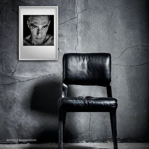 The framed A3 print of Derek Jarman displayed in a distressed interior space. The stark black and white studio portrait resonates with emotional depth, aligning with the raw honesty that defined Jarman’s artistic legacy.