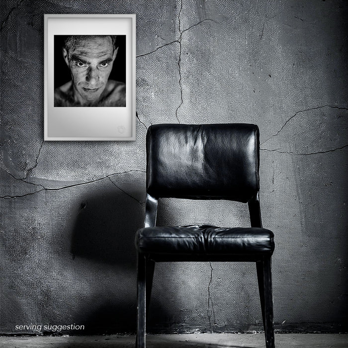 The framed A3 print of Derek Jarman displayed in a distressed interior space. The stark black and white studio portrait resonates with emotional depth, aligning with the raw honesty that defined Jarman’s artistic legacy.
