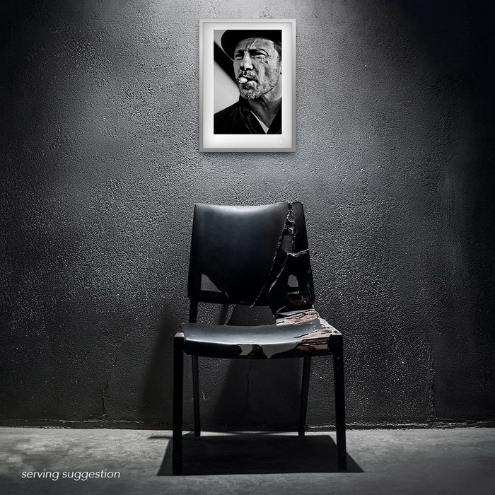 The Harvey Keitel A3 portrait, framed and displayed in a distressed interior. The black and white image — cigar in hand, eyes locked on the lens — exudes raw cool against a backdrop of gritty elegance.
