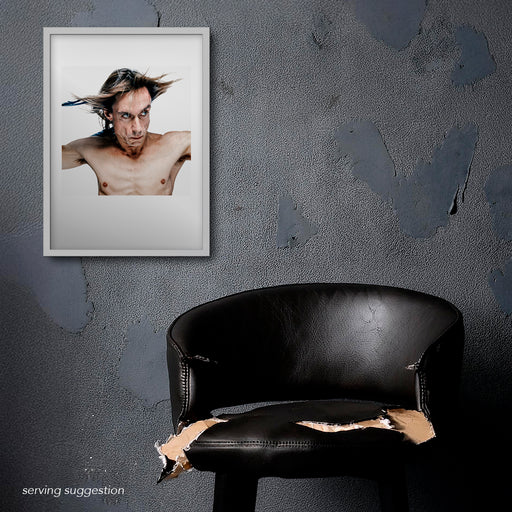 Framed colour portrait of Iggy Pop by Gavin Evans, 1996. Dynamic pose, feathers and bare chest in distressed room, Iggy Pop Collection.