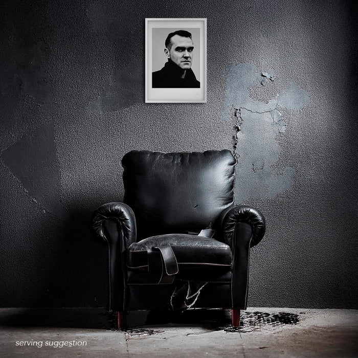 Intense B&W studio portrait of Morrissey by Gavin Evans, 1997. Direct gaze, graphic lighting, Icons Collection. Displayed framed in a distressed room setting for visual context.