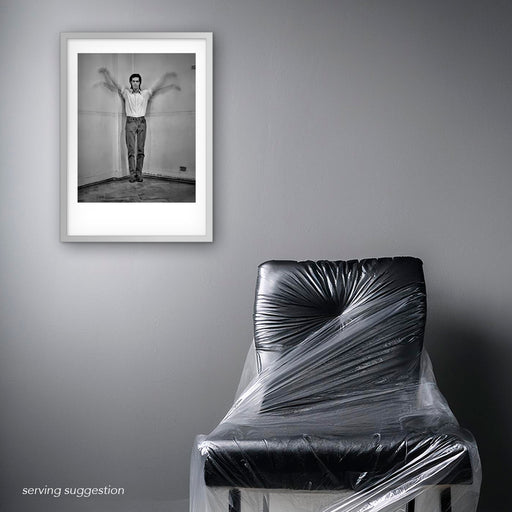 Framed B&W portrait of Nick Cave by Gavin Evans. Arms lifted in winged gesture. Displayed in monochrome room, Nick Cave Collection.