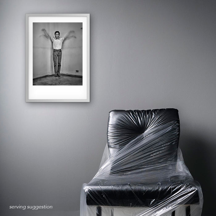 Framed B&W portrait of Nick Cave by Gavin Evans. Arms lifted in winged gesture. Displayed in monochrome room, Nick Cave Collection.