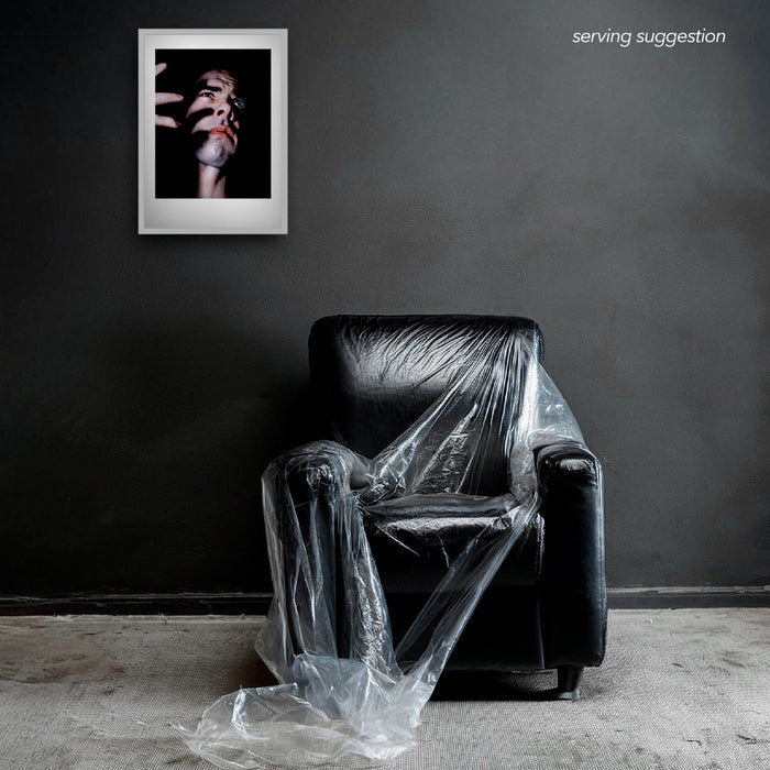 Framed colour semi-profile of Nick Cave by Gavin Evans. Fingers cast shadows across face. Displayed in monochrome room, Nick Cave Collection.