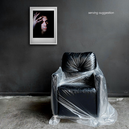 Framed colour portrait of Nick Cave by Gavin Evans. Piercing gaze, hand with cigarette on forehead. Displayed in monochrome room, Nick Cave Collection.