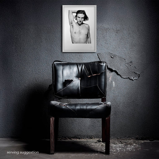 Framed display of the Ralph Fiennes A3 fine art print in a raw, textured room. The stark studio lighting and white background heighten the intensity of the portrait, offering a dramatic visual centrepiece.