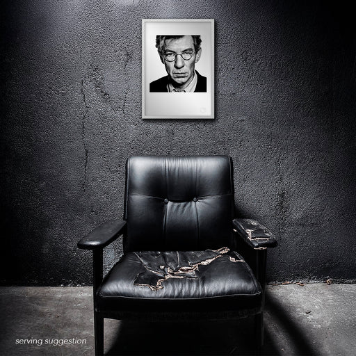 Framed version of the Sir Ian McKellen A3 fine art print shown in a raw, textured space. The intimate 1996 studio portrait’s dramatic contrast adds intensity and presence to any environment.