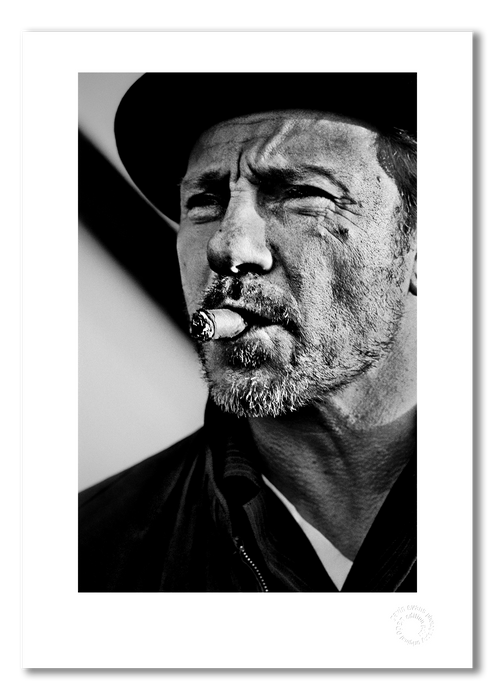A3 open edition fine art print of Harvey Keitel smoking a cigar, featuring a white border and printed on semi-matt archival cotton paper. This 1986 black and white portrait by Gavin Evans is full of attitude and cinematic cool. Embossed for authenticity.