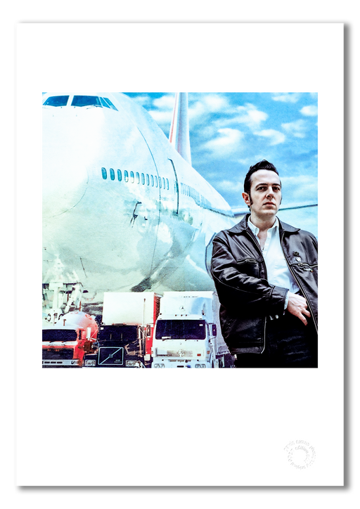 Colour portrait of Joe Strummer by Gavin Evans, 1988. Reaching into jacket, brooding energy. A3 giclée print with white border, Icons Collection.