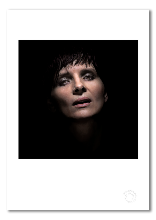The A3 fine art print of Juliette Binoche as presented with a white border, printed on semi-matt archival cotton paper. Photographed in Paris in 2015 by Gavin Evans, this image captures the celebrated actress emerging from darkness, embossed for authenticity.