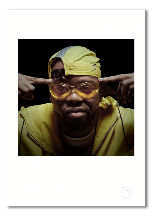 Colour portrait of Method Man by Gavin Evans, 1997. Yellow jacket, sunglasses, forefingers to temples. A3 giclée with white border, Icons Collection.